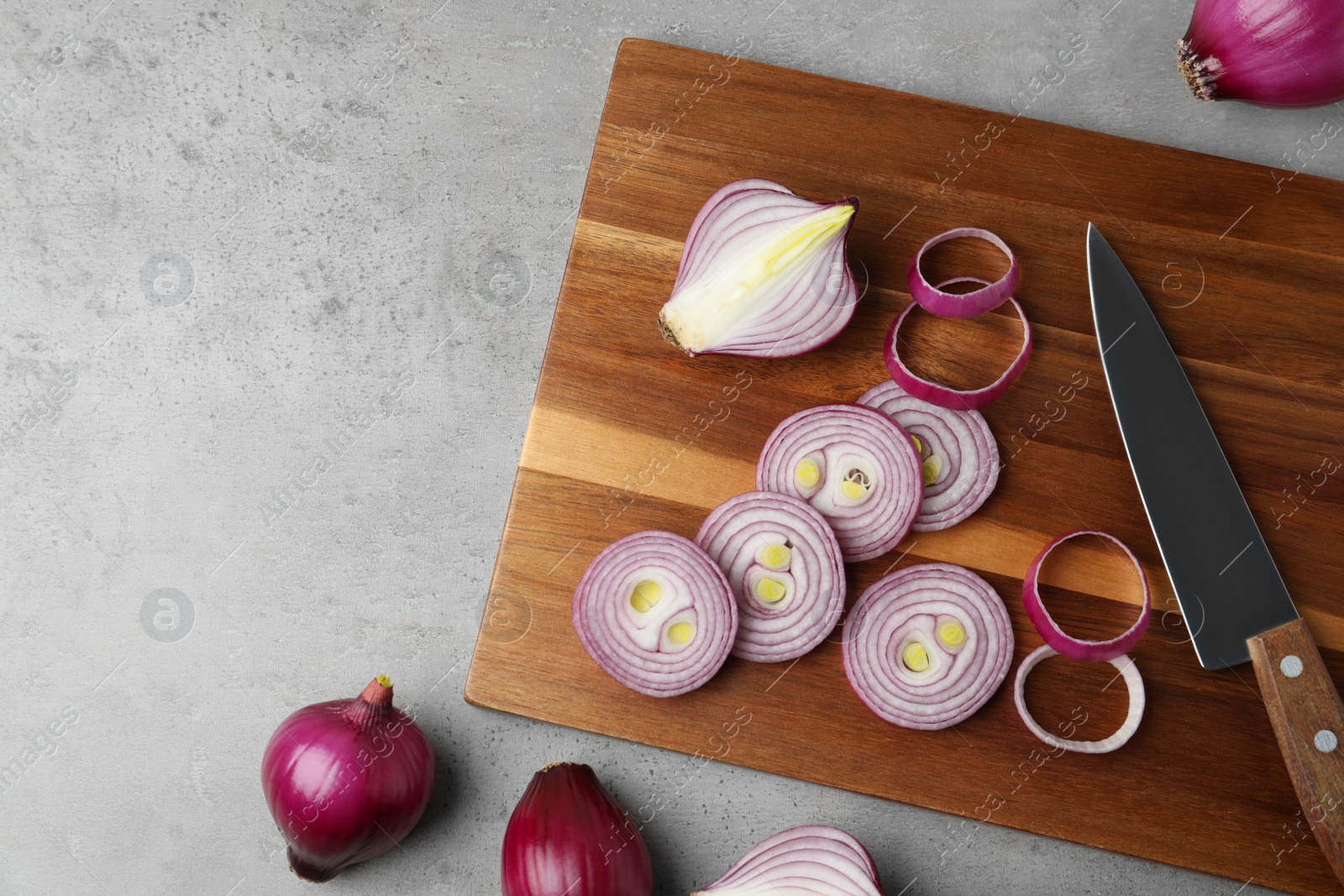 Photo of Red onion and wooden board on light grey table, flat lay