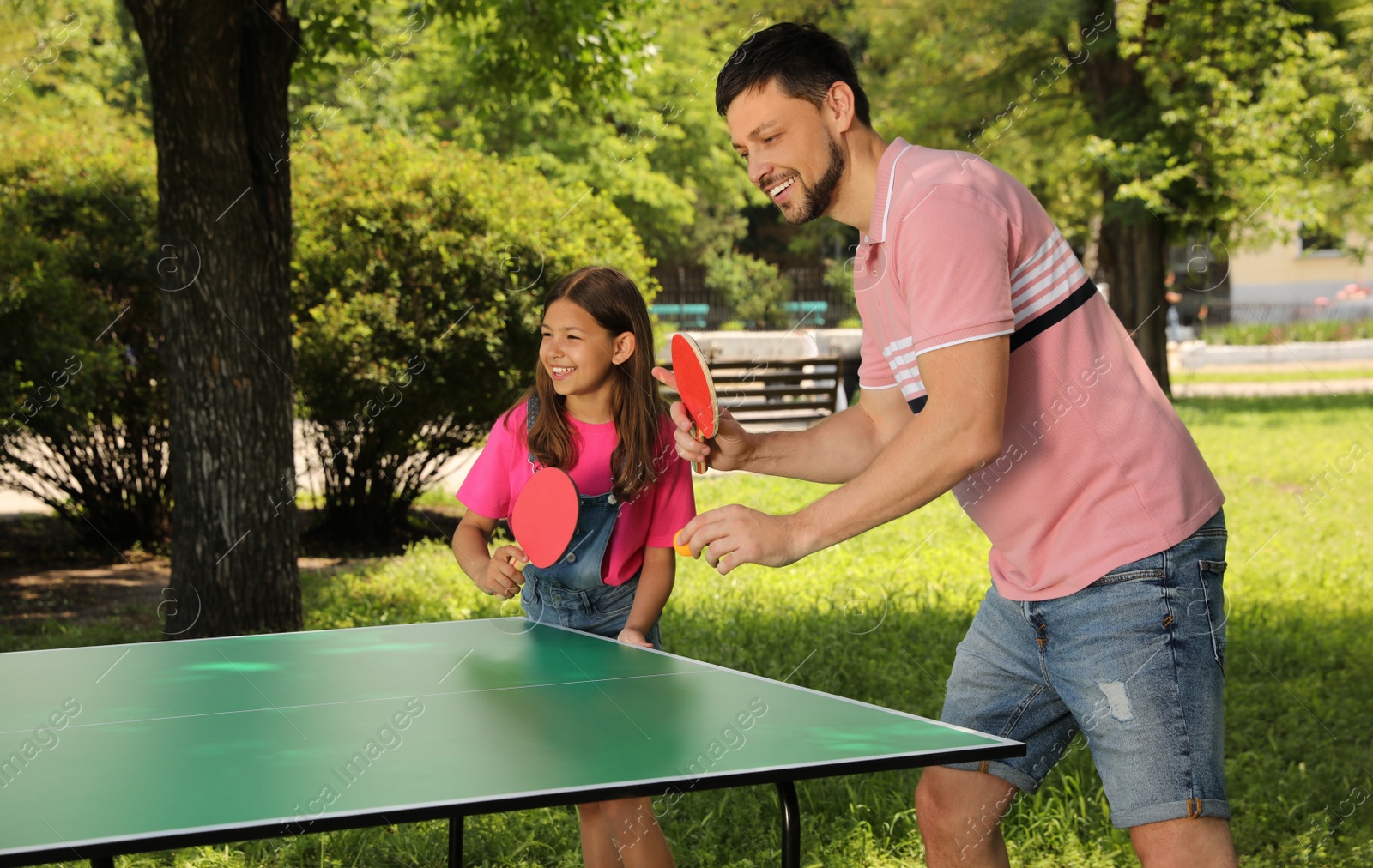 Photo of Happy man with his daughter playing ping pong in park