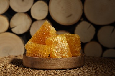 Photo of Natural honeycombs on wicker mat near woods, closeup