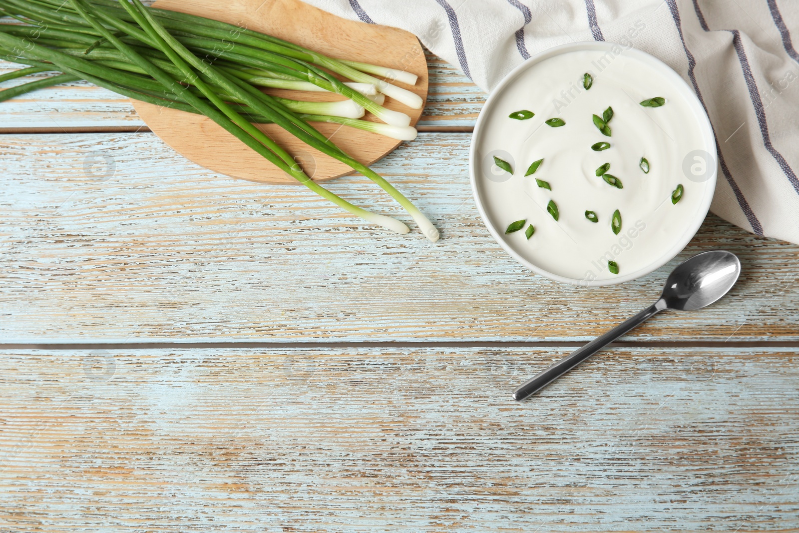 Photo of Flat lay composition with sour cream and green onion on light blue wooden table, space for text