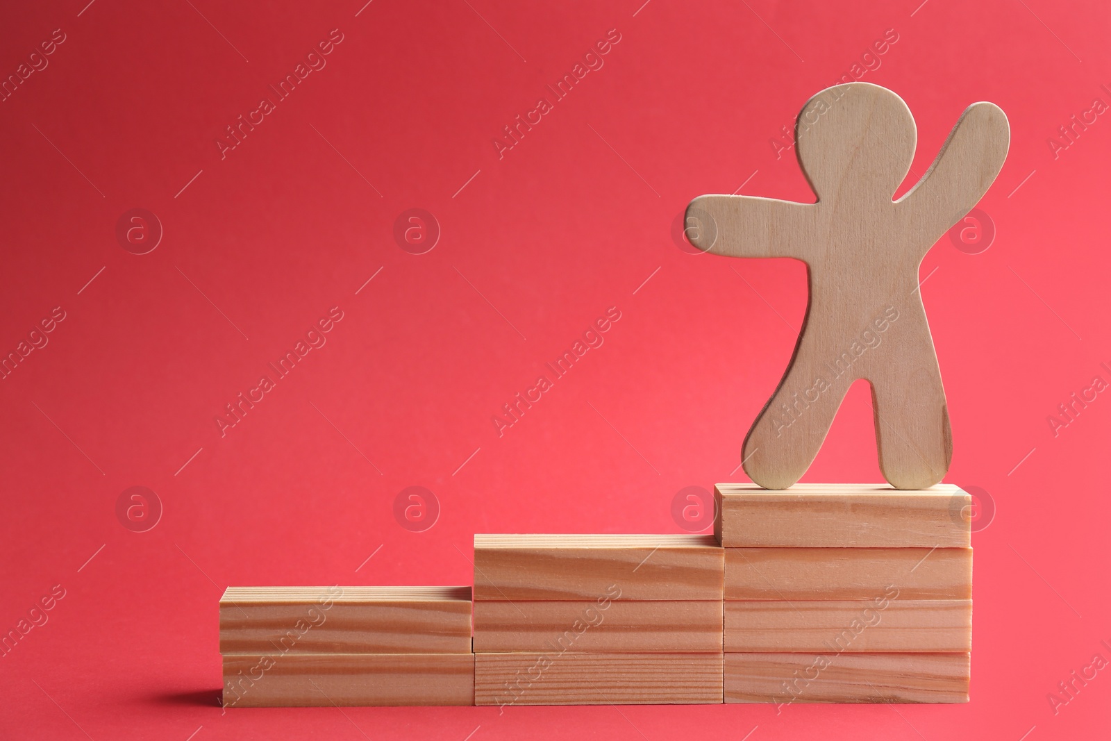 Photo of Wooden human figure on top of stairs against red background. Career promotion concept