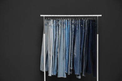 Rack with different jeans on dark grey background