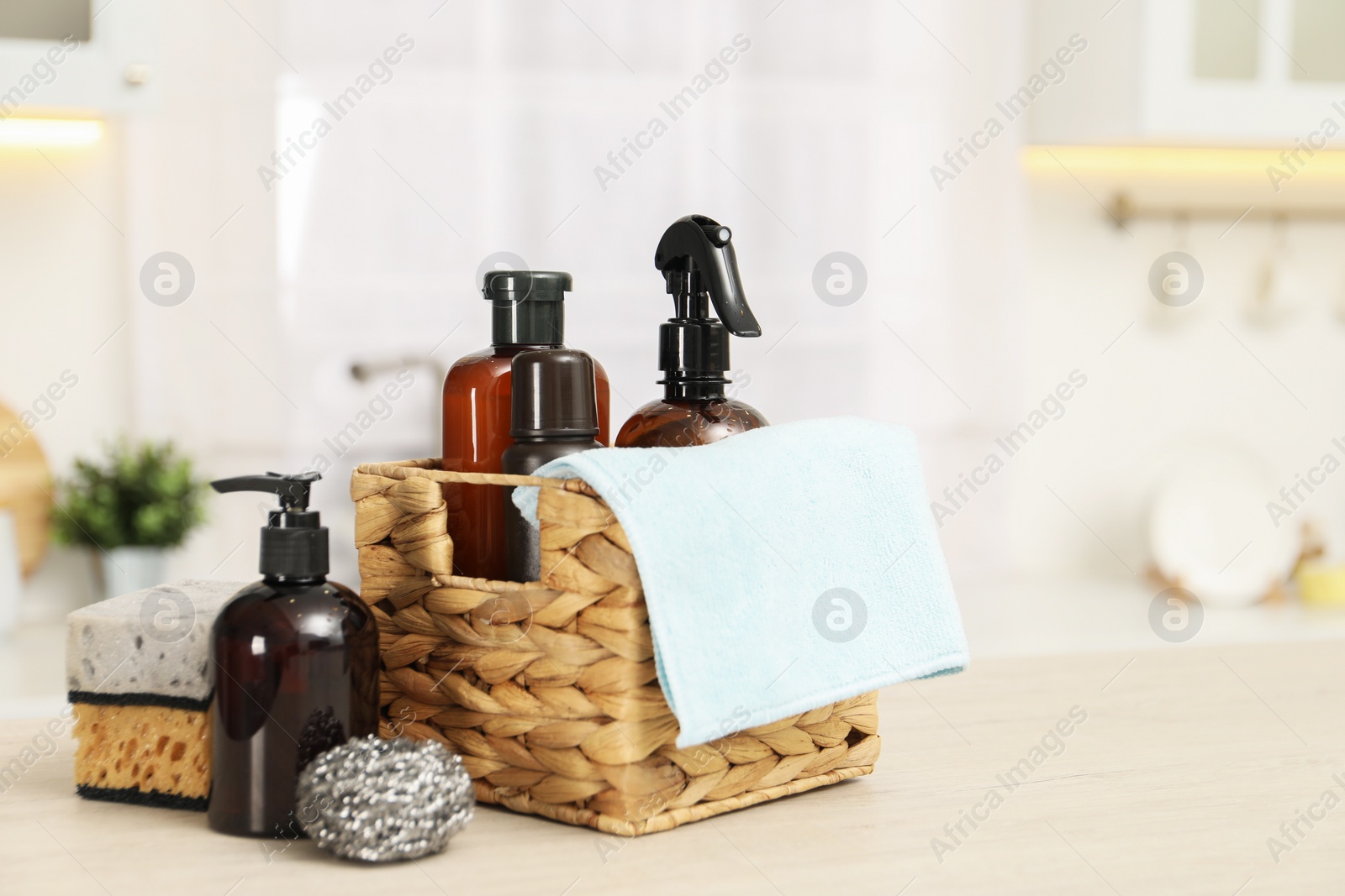 Photo of Different cleaning supplies in basket on table. Space for text