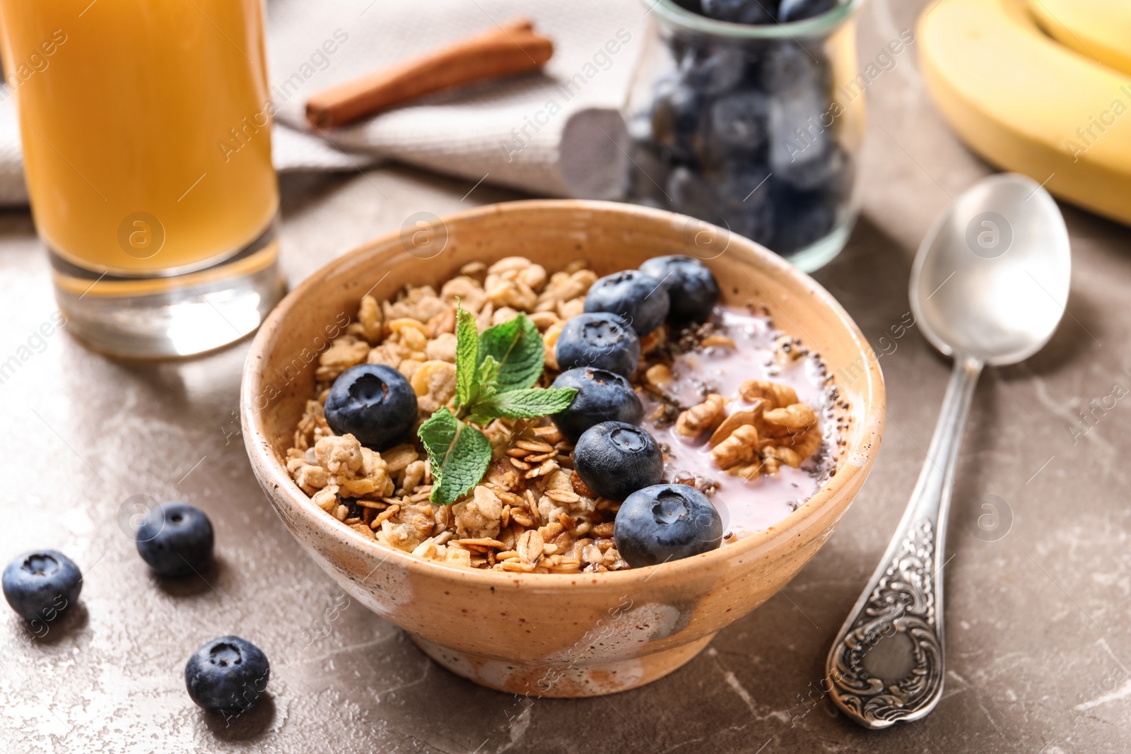 Photo of Bowl of tasty oatmeal with blueberries and yogurt on marble table