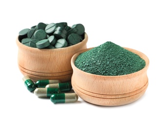 Photo of Wooden bowls of spirulina pills and powder on white background