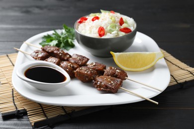 Tasty chicken meat glazed in soy sauce served with rice on black wooden table, closeup