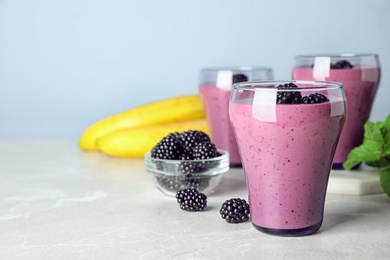 Delicious blackberry smoothie in glasses and ingredients on marble table