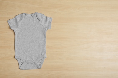 Photo of Cute baby onesie on wooden background, top view. Space for text