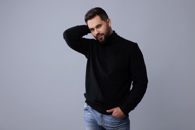 Handsome man in stylish black sweater on grey background