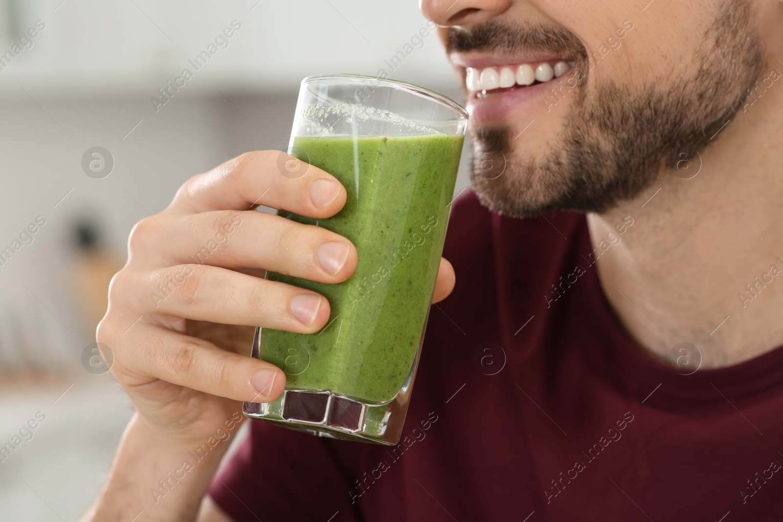 Photo of Happy man drinking delicious fresh smoothie indoors, closeup