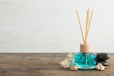 Aromatic reed freshener, spa stones and sea shells on wooden table against light background. Space for text