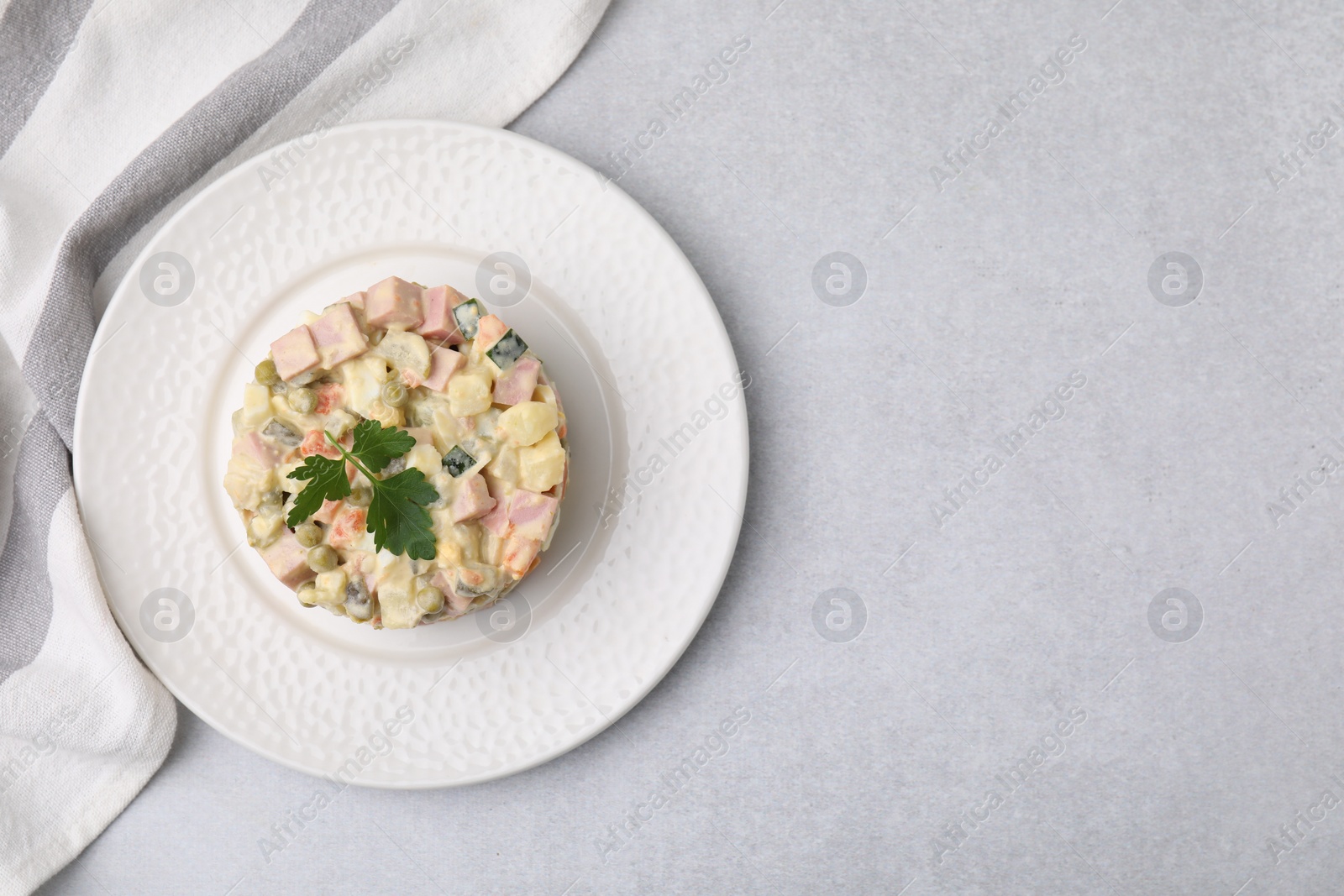 Photo of Tasty Olivier salad with boiled sausage on light grey table, top view. Space for text