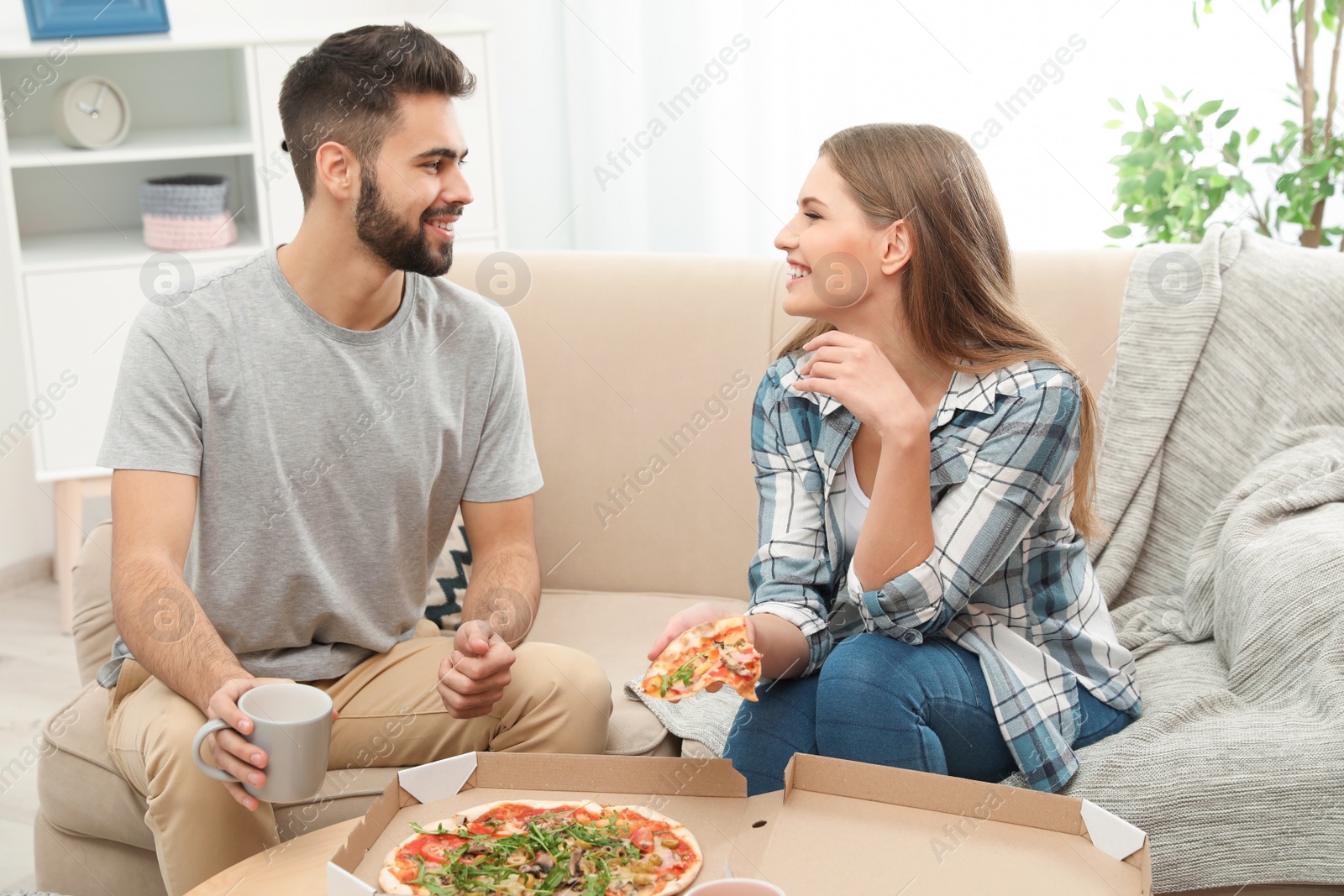 Photo of Young couple having pizza for lunch in living room. Food delivery