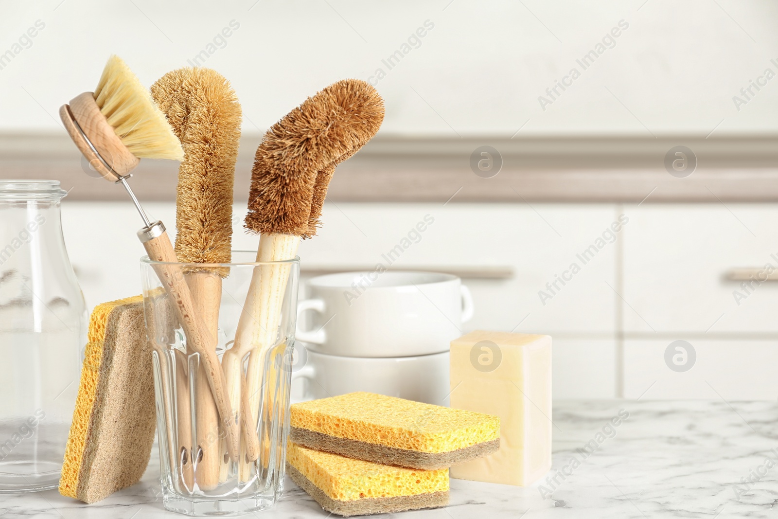 Photo of Cleaning tools on white marble table in kitchen, space for text. Dish washing supplies