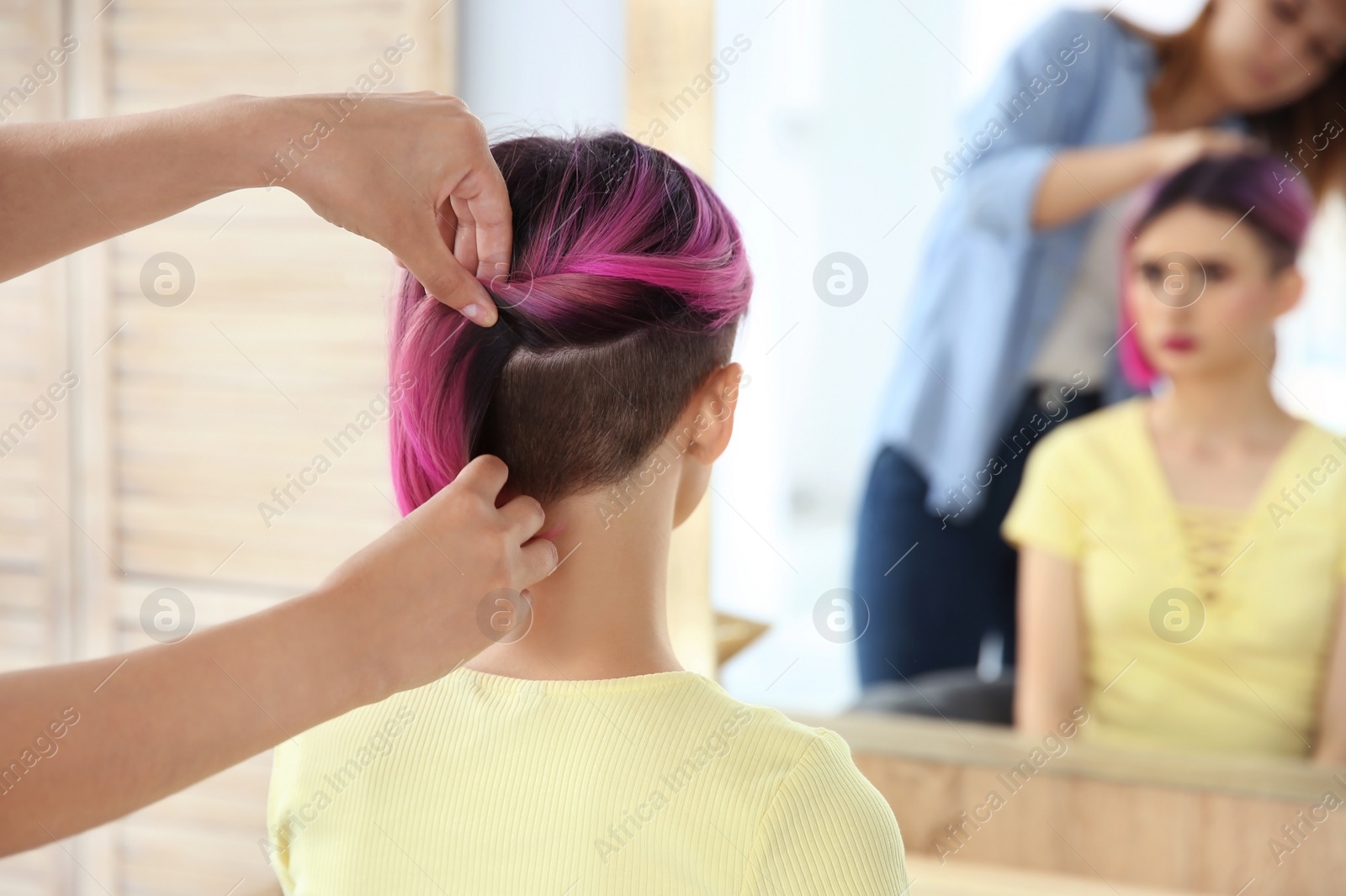 Photo of Professional hairdresser working with young woman in beauty salon. Trendy hair color