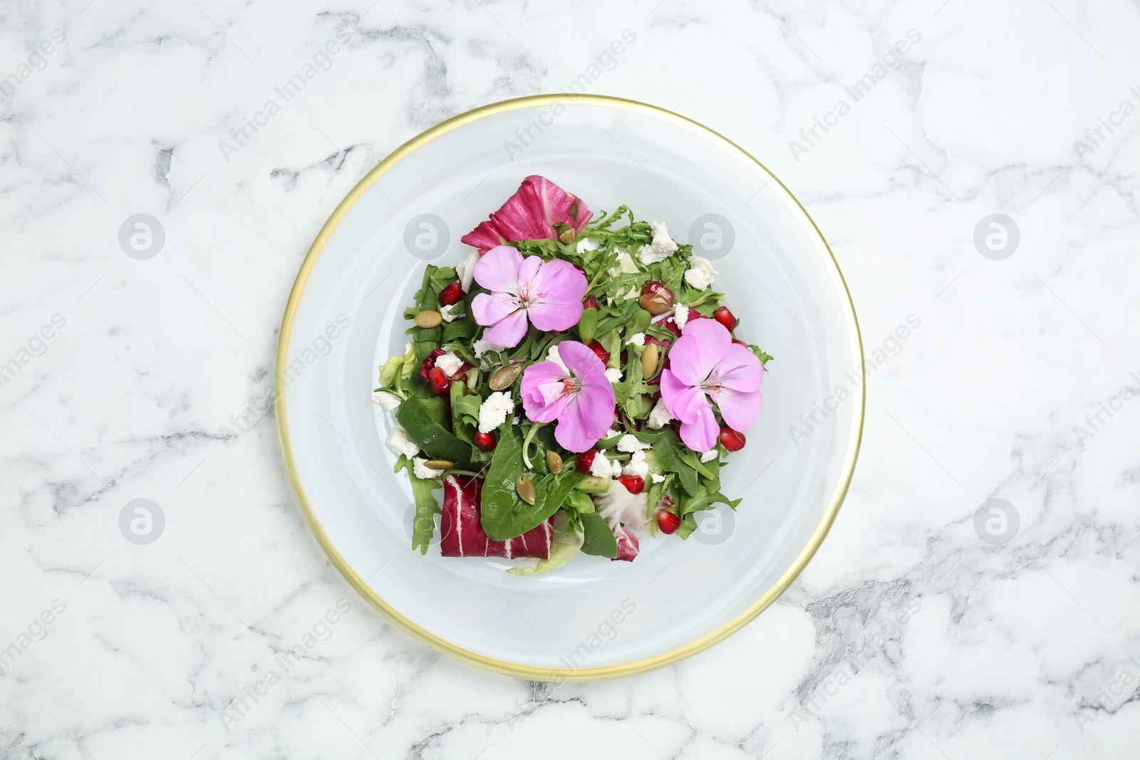 Photo of Fresh spring salad with flowers on white marble table, top view