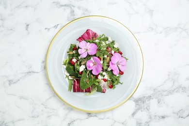Fresh spring salad with flowers on white marble table, top view