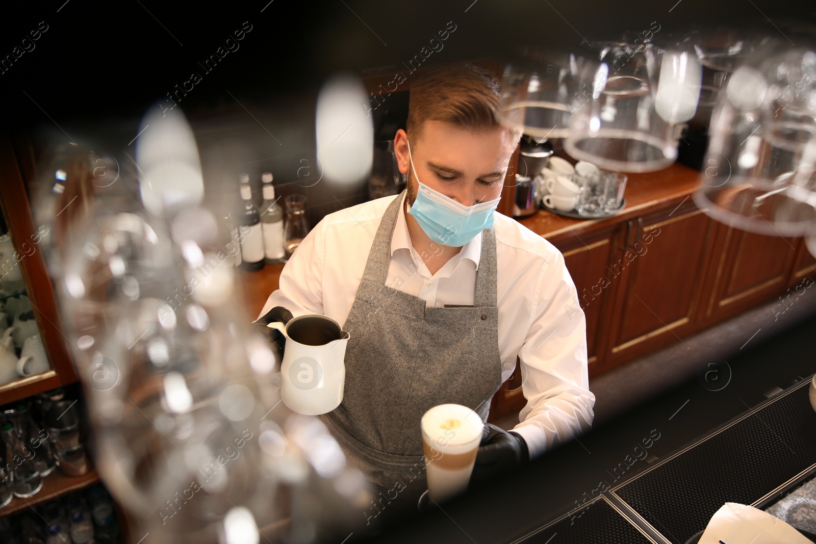 Photo of Barista preparing coffee at counter in restaurant. Catering during coronavirus quarantine