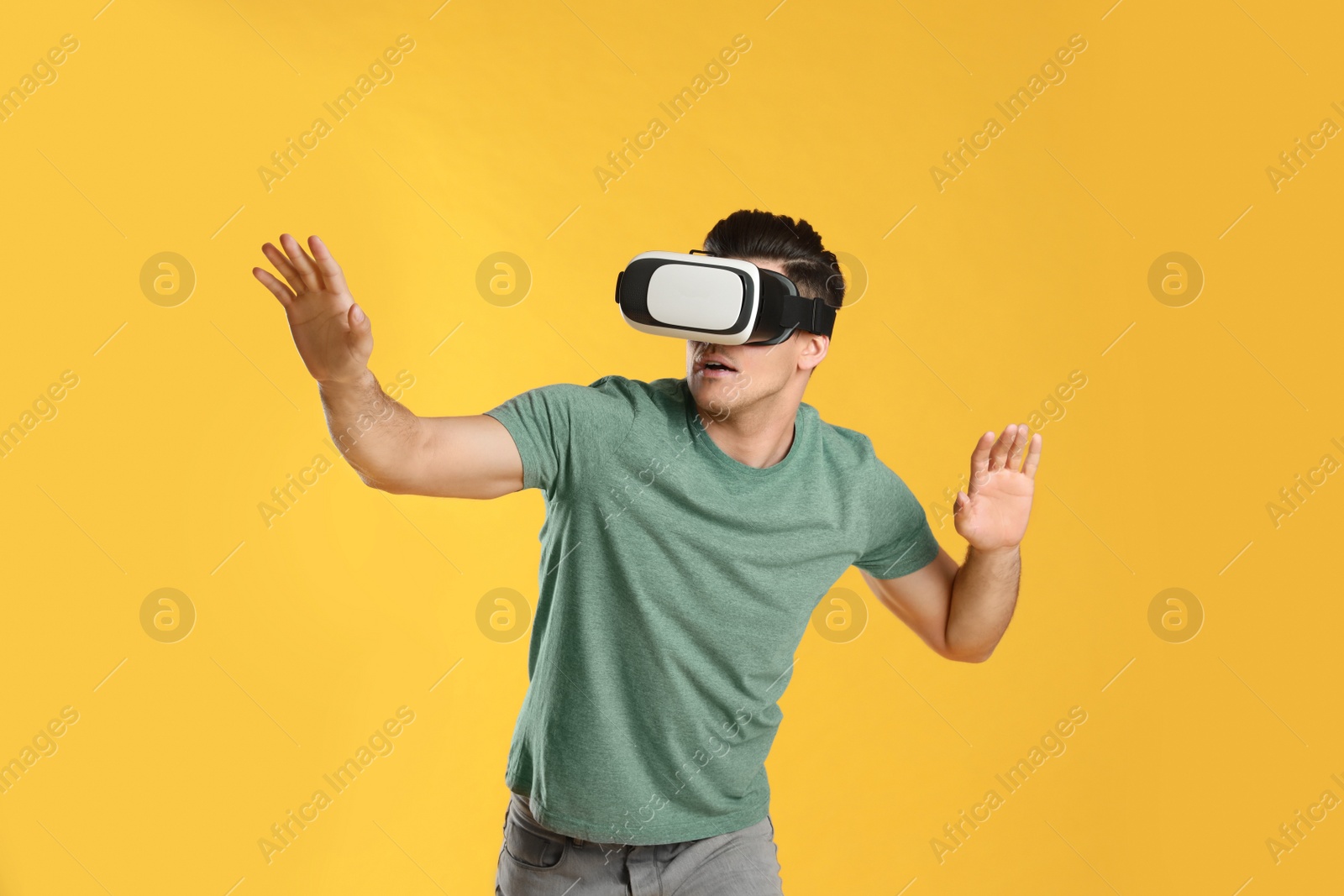 Photo of Man using virtual reality headset on yellow background