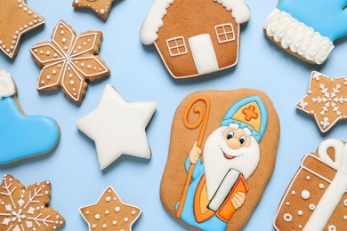 Photo of Tasty gingerbread cookies on light blue background, flat lay. St. Nicholas Day celebration