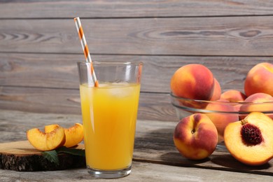Glass of delicious peach juice with ice and fresh fruits on wooden table