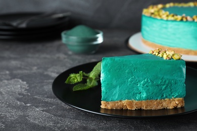 Photo of delicious homemade spirulina cheesecake served on grey table