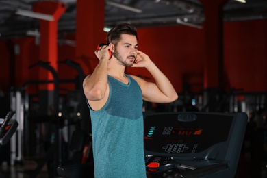Photo of Handsome young man with headphones at gym