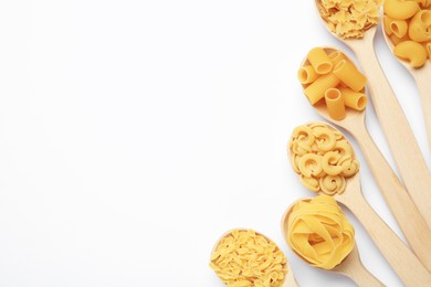 Different types of pasta in spoons on white background, flat lay. Space for text