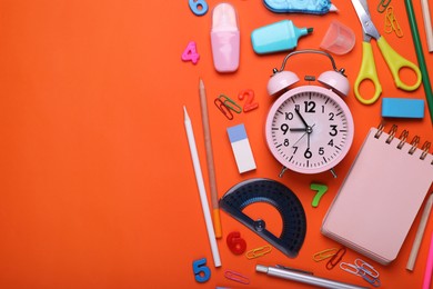 Flat lay composition with different school stationery and alarm clock on red background, space for text. Back to school