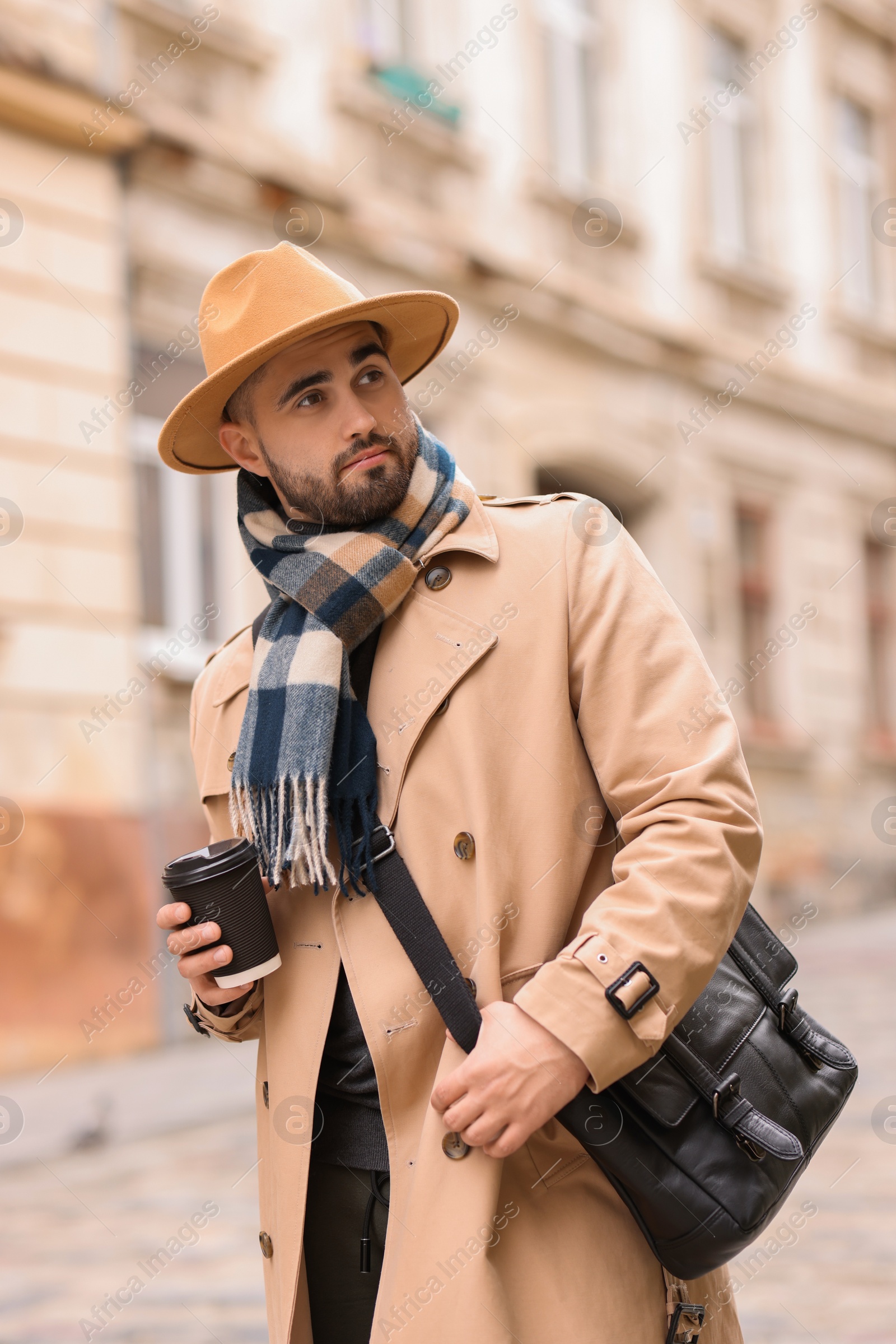 Photo of Handsome man in warm scarf with paper cup outdoors