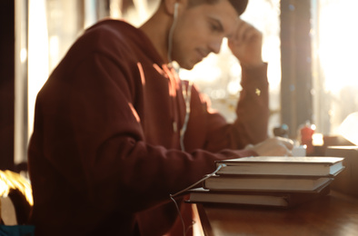 Man with headphones connected to book at table in cafe