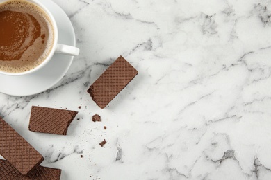 Photo of Delicious chocolate wafers with cup of coffee on marble background, top view. Space for text