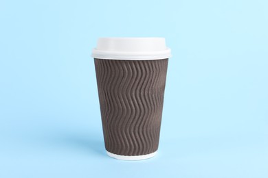 Photo of Brown paper cup with plastic lid on light blue background. Coffee to go