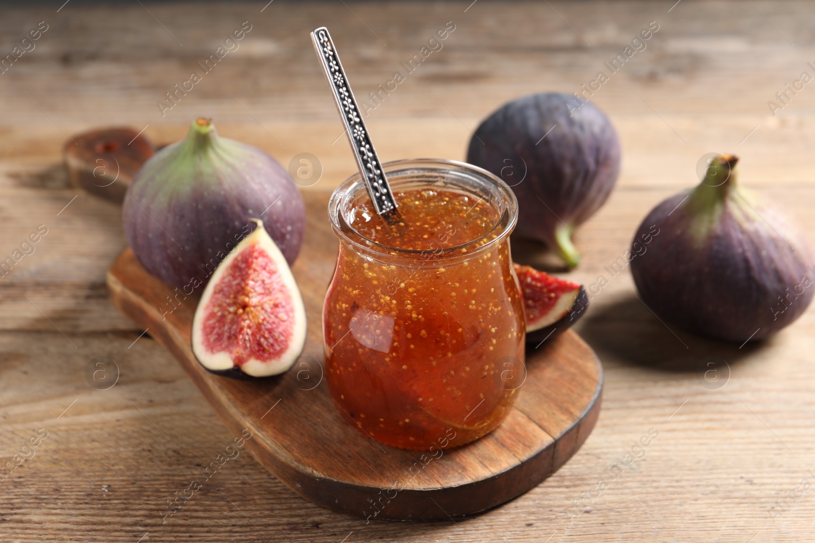 Photo of Glass jar with tasty sweet jam and fresh figs on wooden table