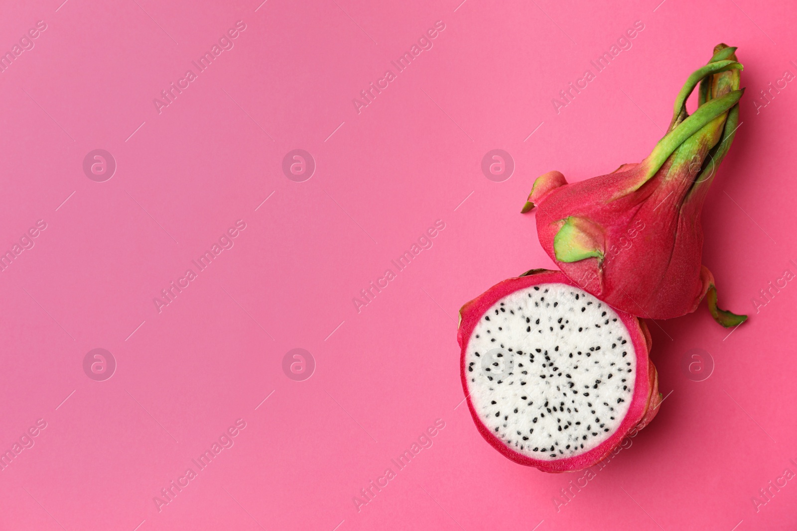 Photo of Halves of delicious ripe dragon fruit (pitahaya) on pink background, top view. Space for text