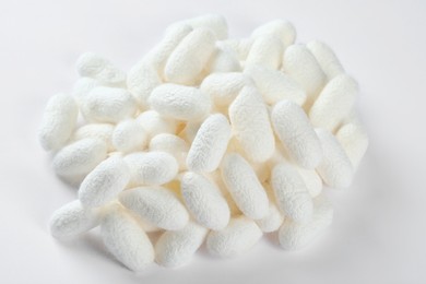 Photo of Pile of natural silkworm cocoons on white background, above view