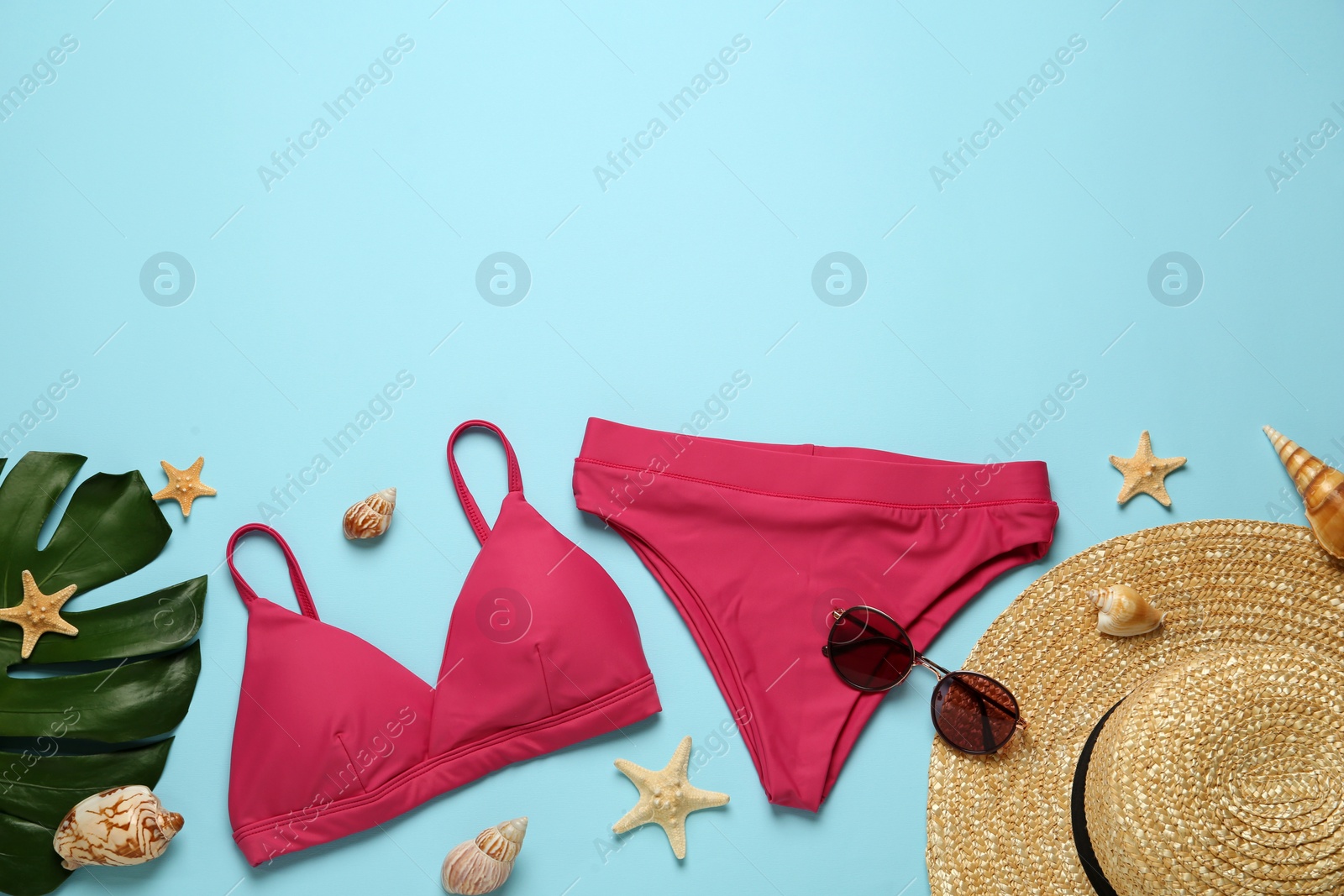 Photo of Stylish bikini and beach accessories on light blue background, flat lay. Space for text