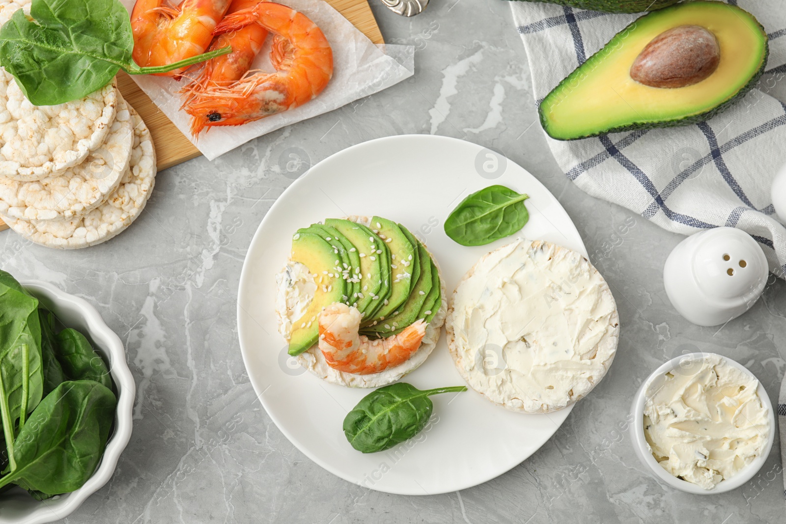 Photo of Puffed rice cake with shrimp and avocado served on grey marble table, flat lay