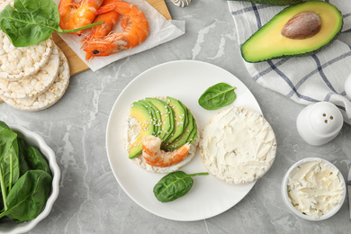Photo of Puffed rice cake with shrimp and avocado served on grey marble table, flat lay