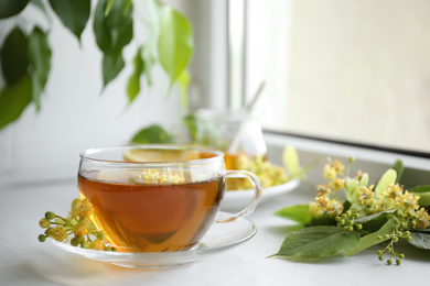 Photo of Cup of tea with linden blossom on white windowsill