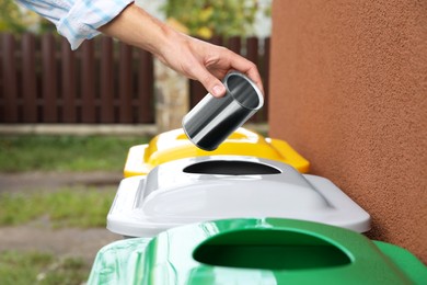 Woman throwing tin can into recycling bin outdoors, closeup