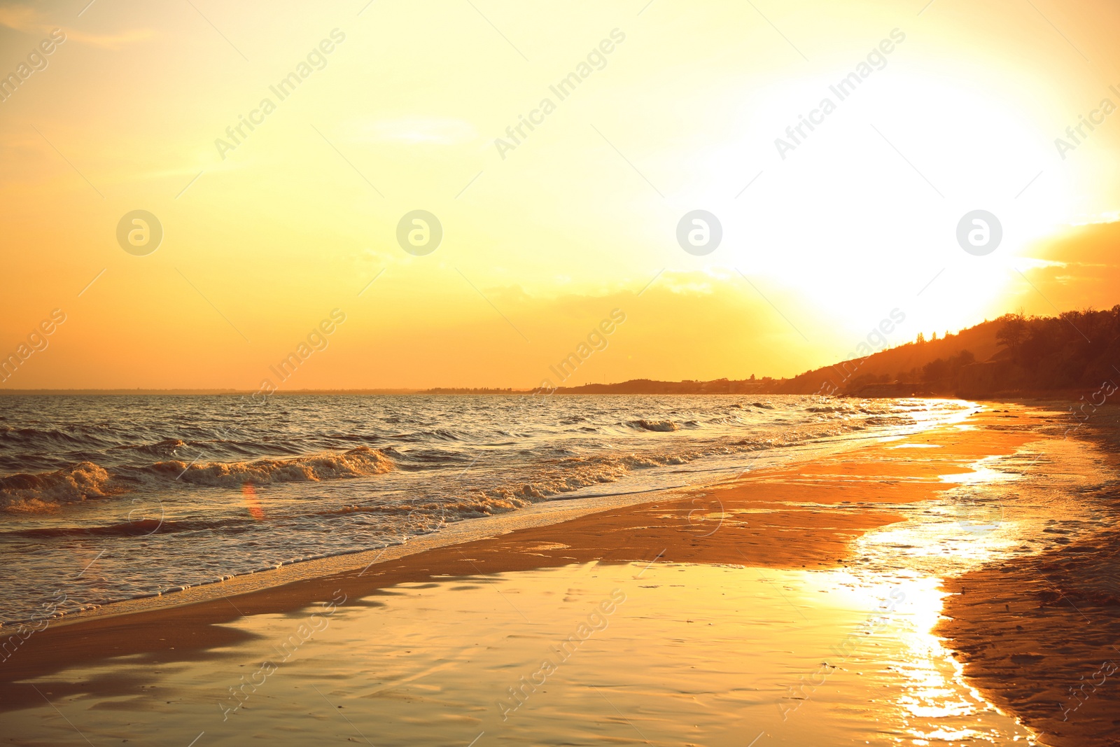 Photo of Picturesque view of sandy beach near sea at sunset