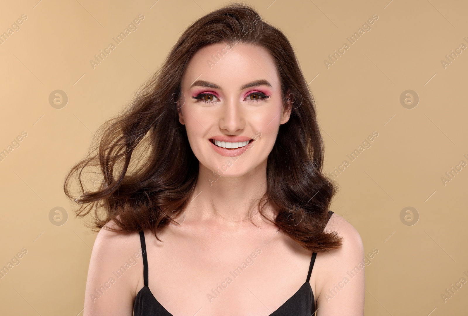 Photo of Portrait of beautiful young woman with makeup and gorgeous hair styling on beige background