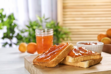 Photo of Bread with tasty apricot jam on wooden board