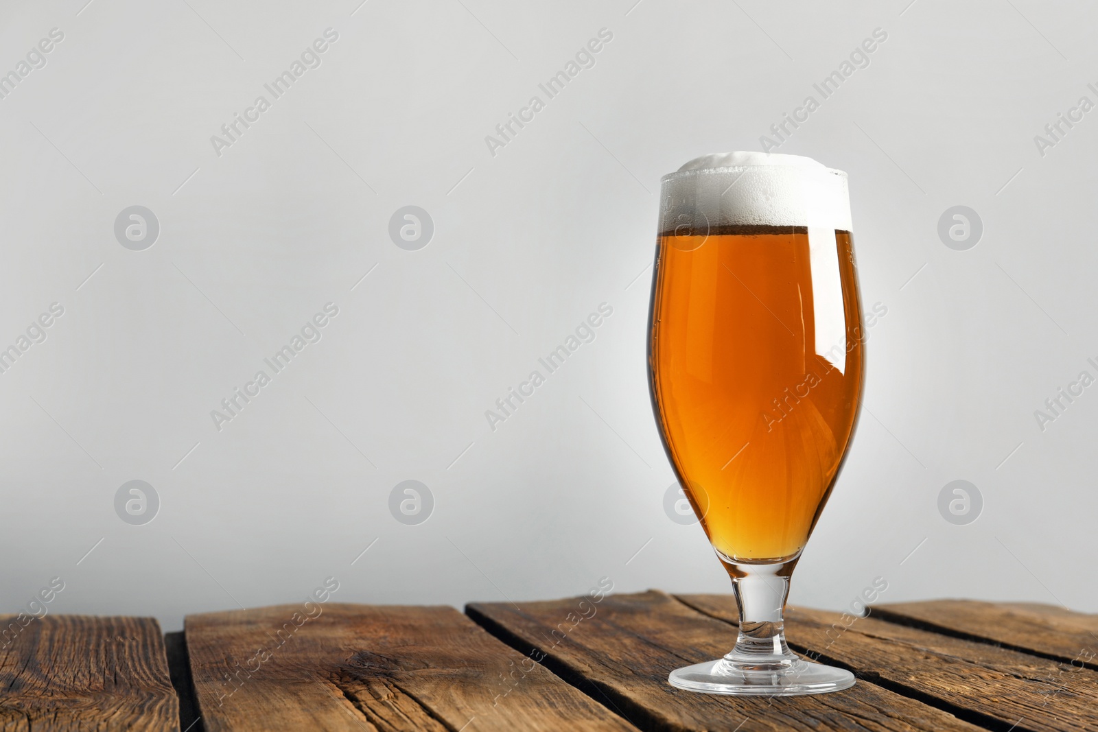 Photo of Glass of tasty beer on wooden table. Space for text