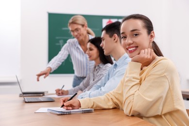 Happy woman making notes at desk in class during lesson in driving school