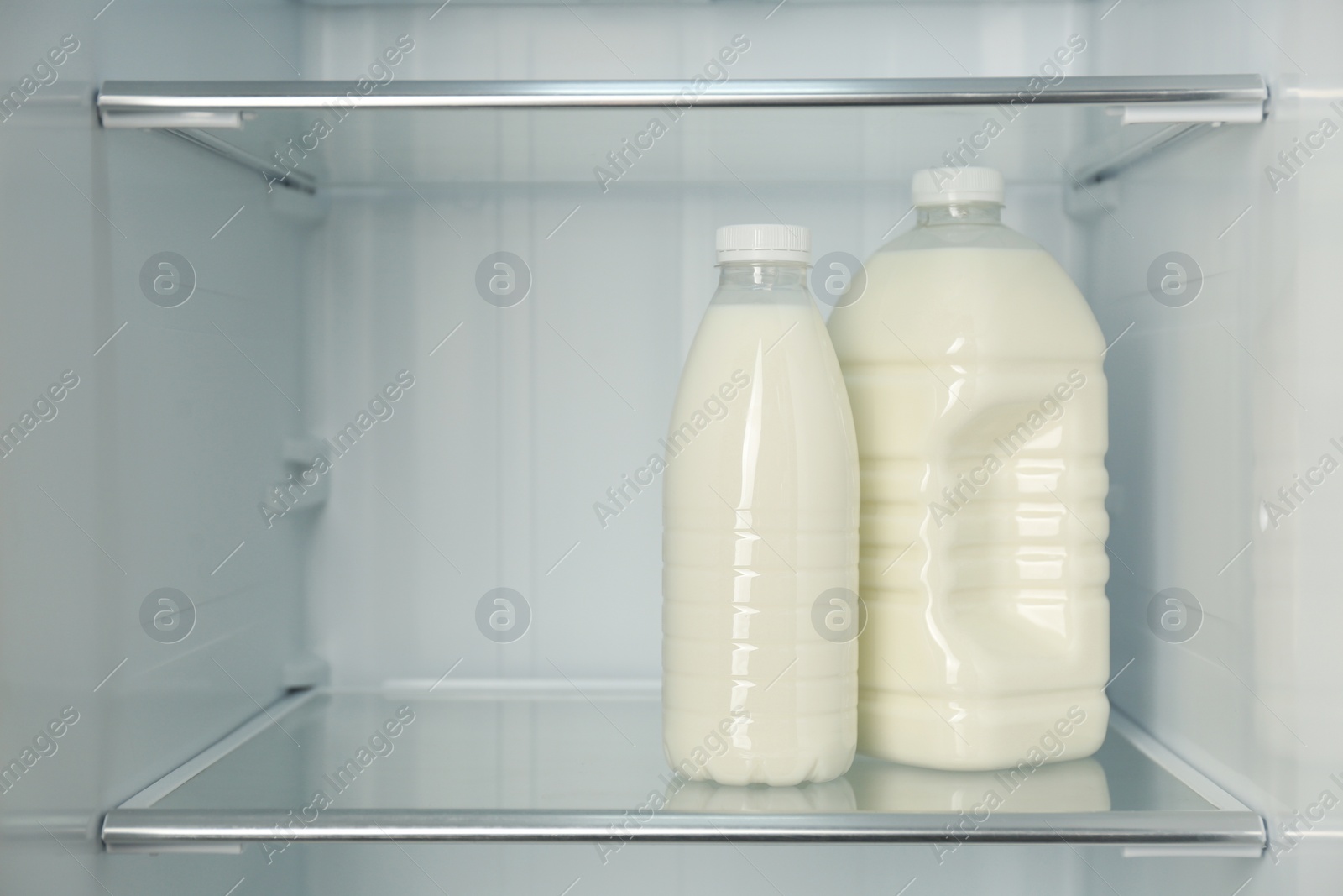 Photo of Gallon and bottle of milk in refrigerator, closeup. Space for text