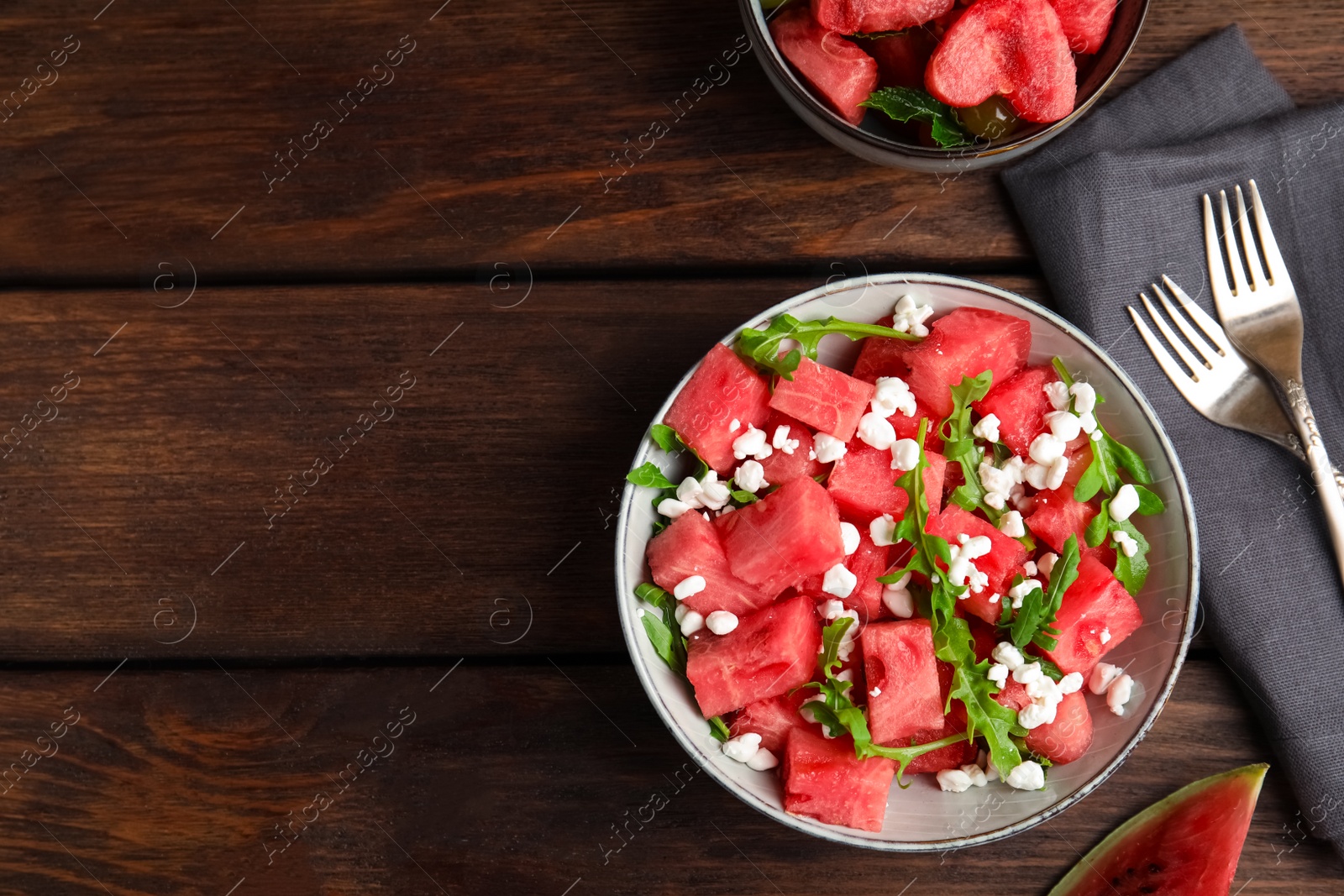 Photo of Delicious salad with watermelon, cheese and arugula on wooden table, flat lay. Space for text