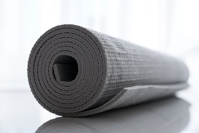 Photo of Rolled karemat or fitness mat on tiled floor, closeup