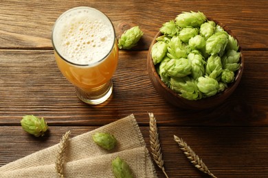 Photo of Glass of beer, fresh green hops and spikes on wooden table, above view
